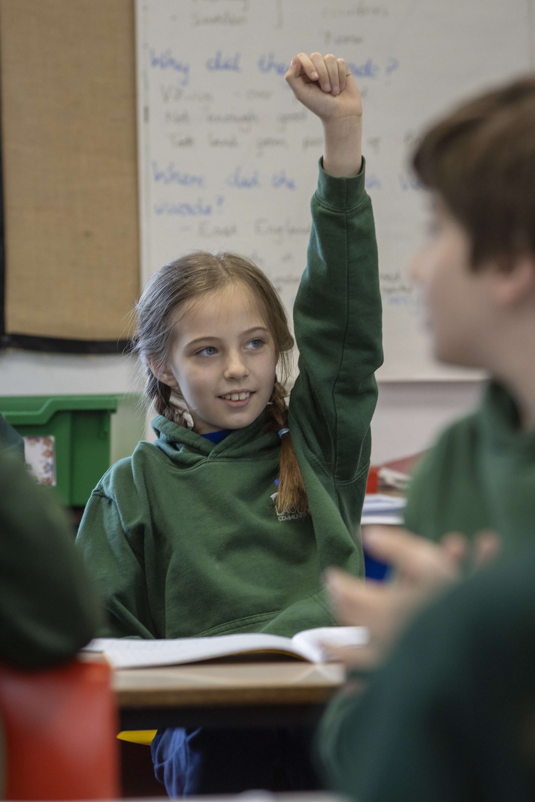 photo of a pupil in a classroom with her hand raised